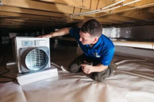 worker checking on crawl space dehumidifier