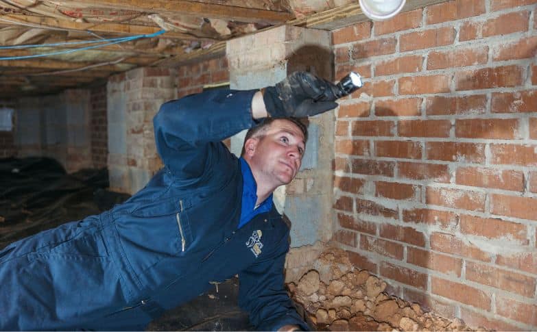 Michael inspects crawl space in blue branded jumpsuit